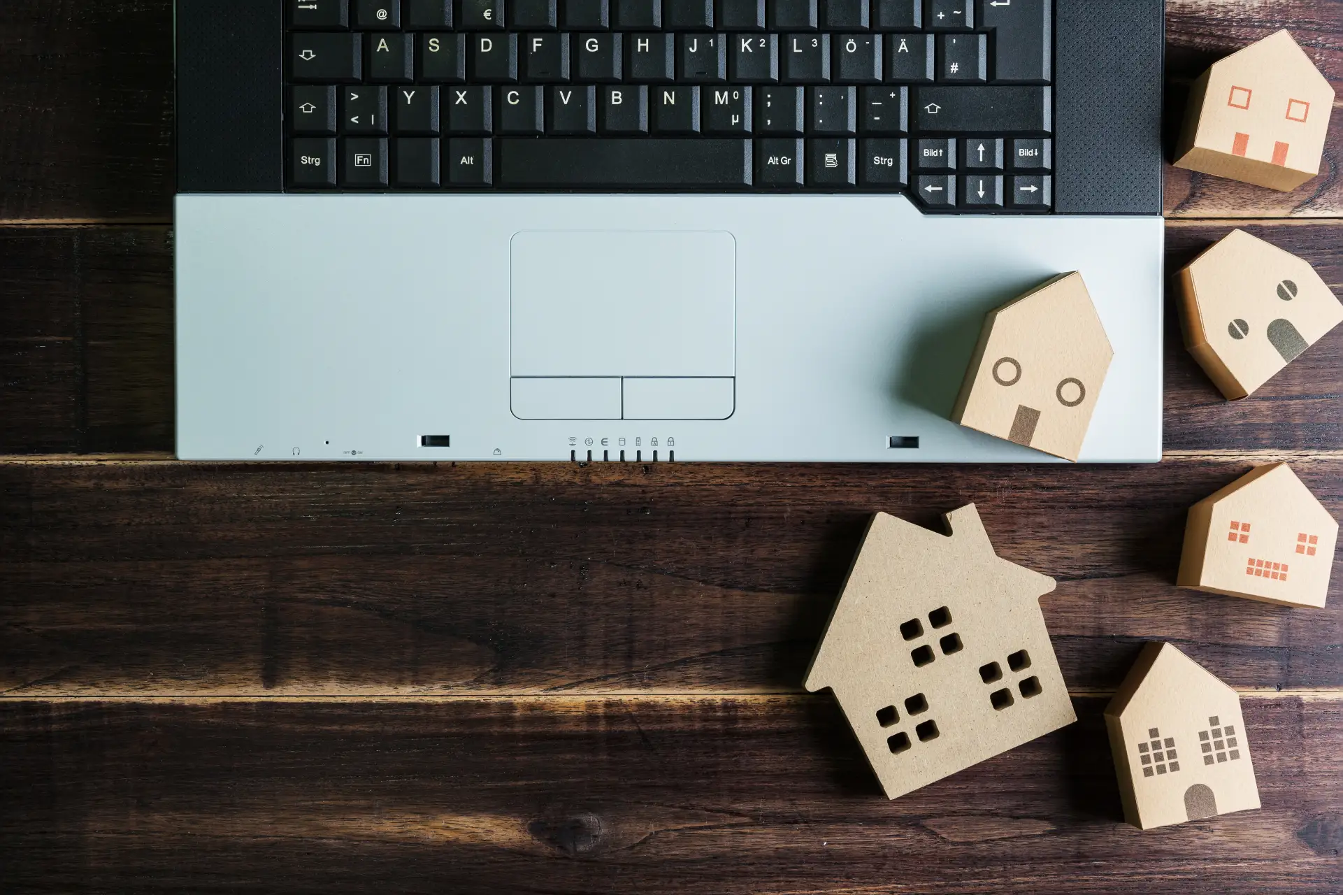 Symbolfoto für Digitalisierung und Datenschutz in Wohnungsbaugenossenschaften – Laptop mit Holzhaus-Modellen